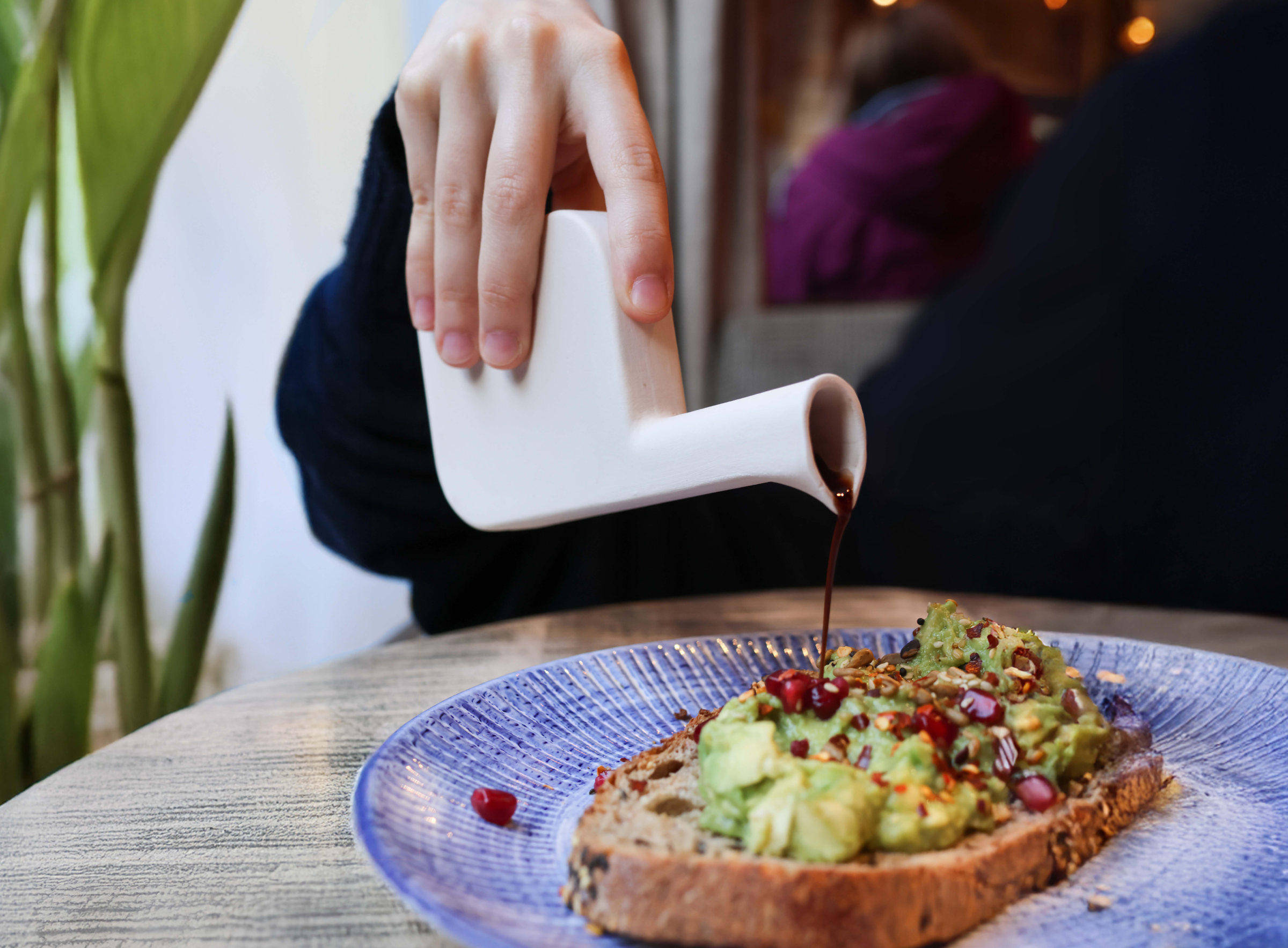 Pouring balsamic vinegar from Ardea onto avocado toast
