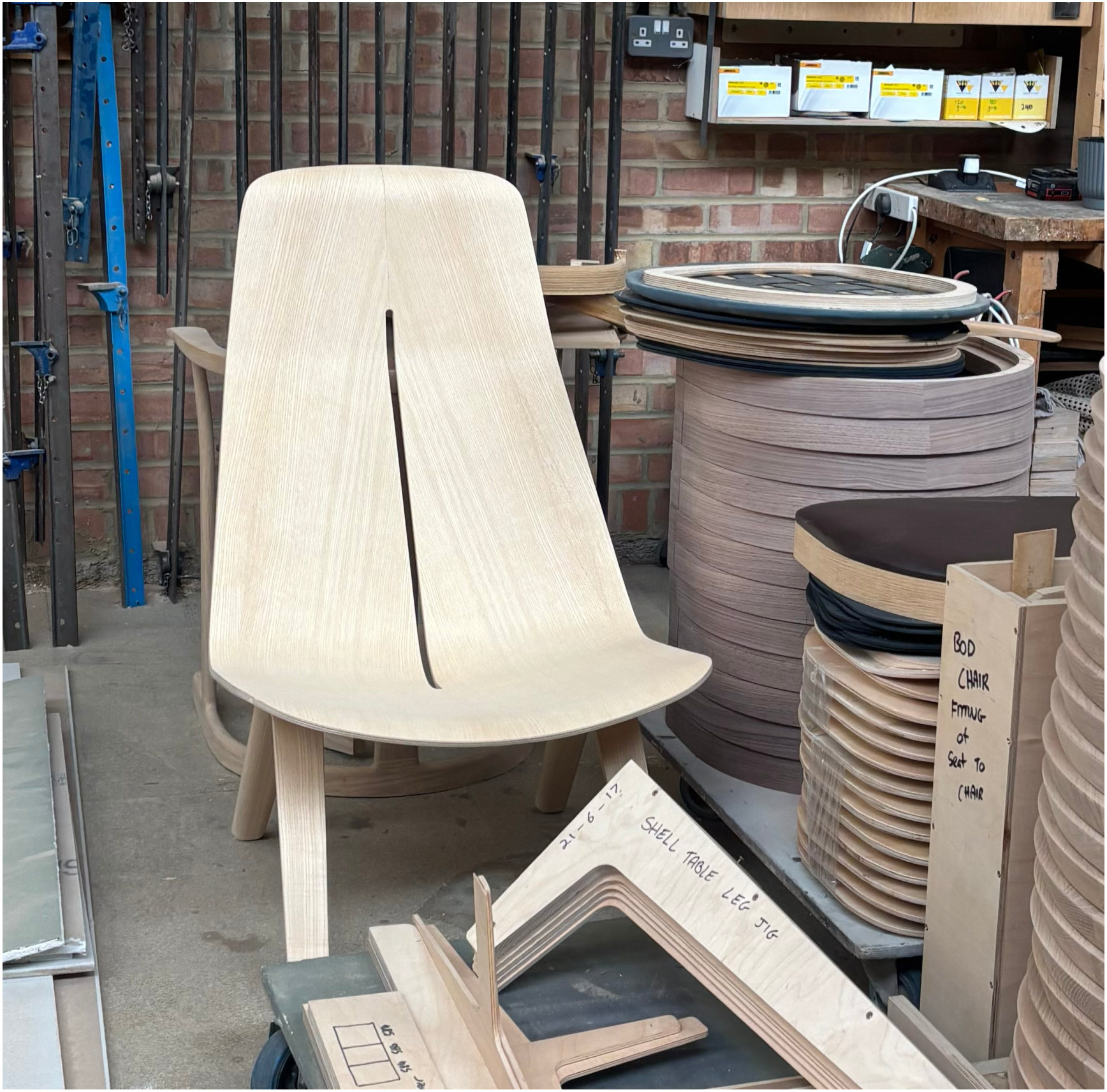 A bent-ply lounge chair beside stacked formers